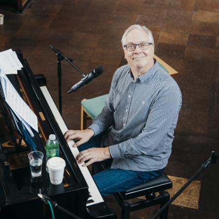 Craig smiles from behind a piano