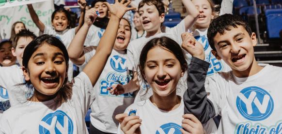 A group of children smile while singing.